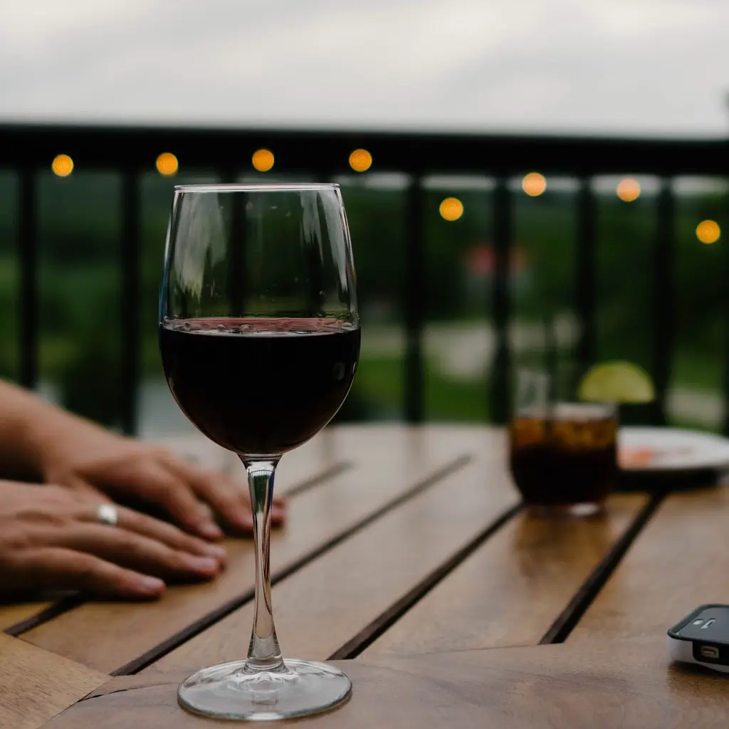 A glass of red wine on a table at dusk