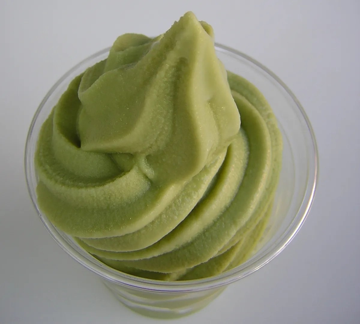 A smooth swirl of matcha soft serve in a clear cup
