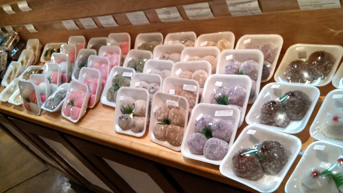 Rows of boxed mochi in different colours on a shop counter
