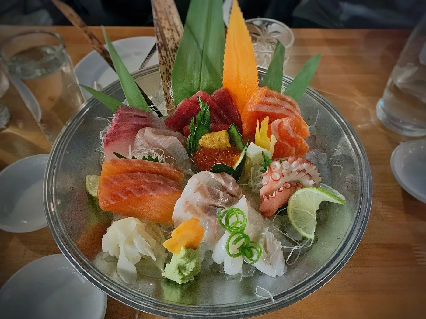 A platter of sashimi on ice with citrus and shiso leaves