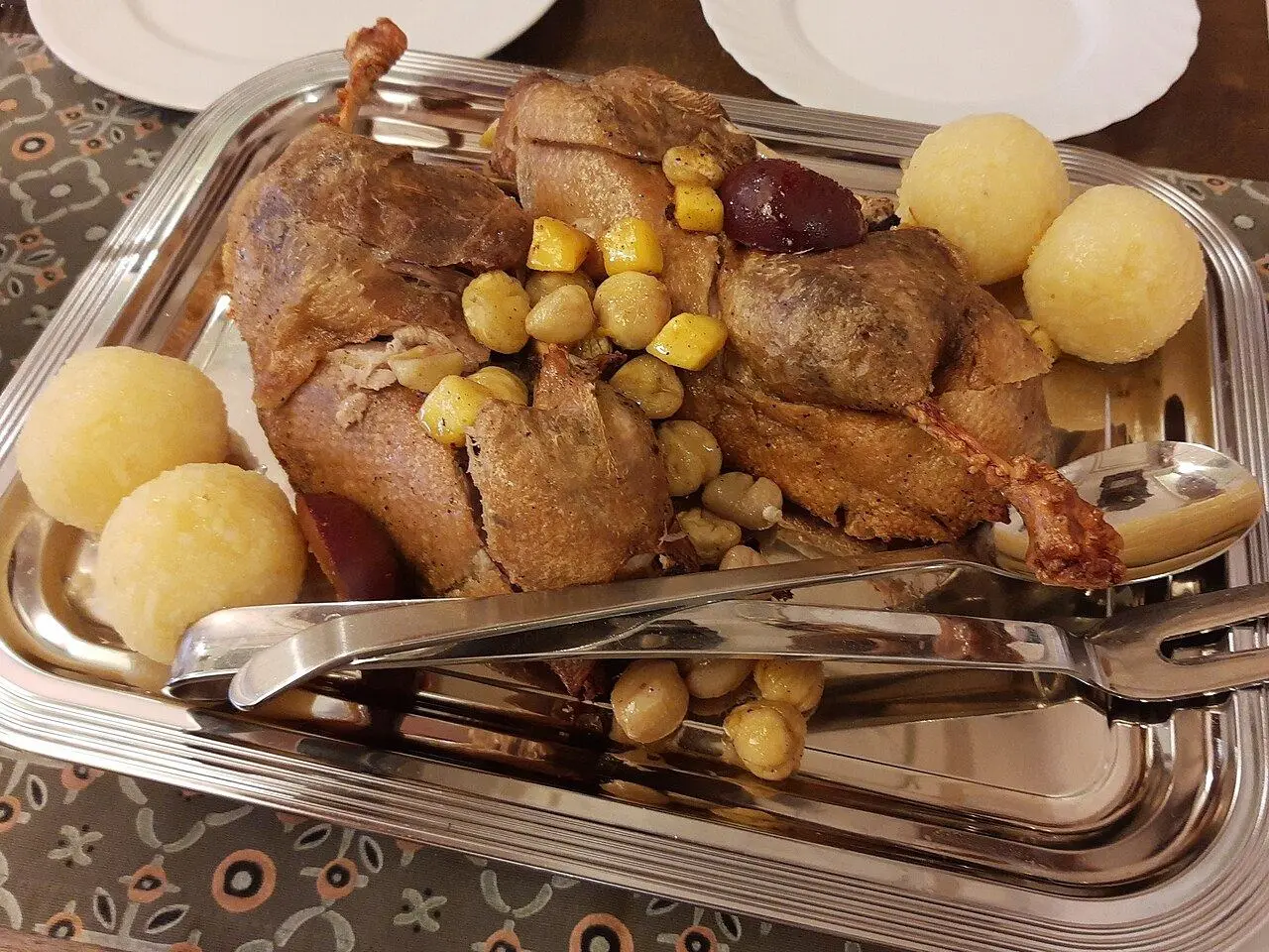 Roast duck with chestnuts and potato dumplings on a silver platter